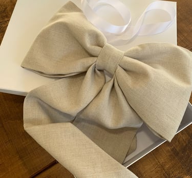 A large bow made from neutral coloured linen on a box