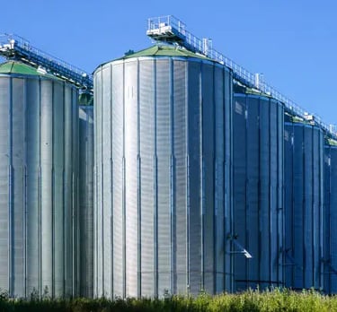 a large group of metal tanks with a blue sky in the background