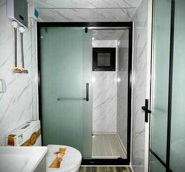 Modern small bathroom interior featuring a frosted glass sliding shower door and marble-patterned walls.