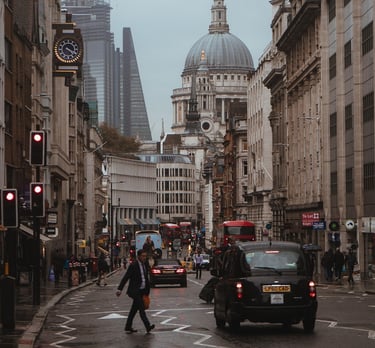 A man crossing a London street. We also see a Black Cab, Red Bus, and the top of St Paul's Cathedral