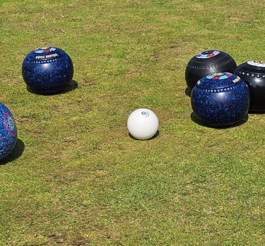 A collection of lawn bowls surrounding a white jack at porthcawl bowls club