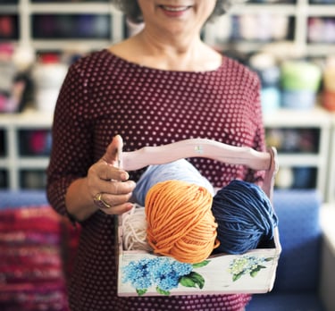 una mujer con un conetedor de madera con varios estambres