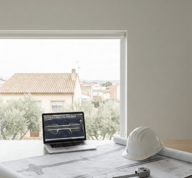 Planos de ingeniería civil y equipo técnico en oficina para planificación de obra en Sevilla.