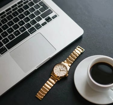 Top-view photography of a workspace with a laptop, a gold watch, and a cup of coffee on a dark surface, representing the busy lifestyle of a Dubai professional.