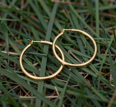 Elegant pair of silver hoop earrings displayed on a minimalist marble surface with soft natural light.