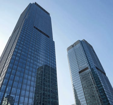 Low-angle view of modern blue glass skyscrapers in Singapore's business district against a clear sky.