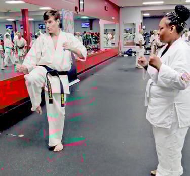 Sensei Mike Theiros demonstrating a kick to a white belt student at Kyokushin Karate USA in Rochester NY