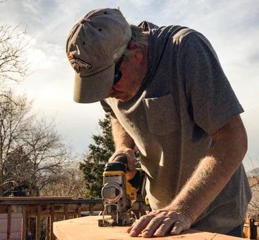 Brewer Construction carpenter using an impact driver on a wooden deck structure in Evergreen.