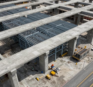 Overhead drone photography of a North American transit hub under construction. The complex geometry of the concrete footings and steel frames shows technical mastery and scale.