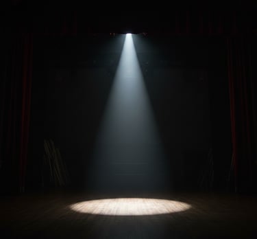 A single bright theater spotlight shining on an empty wooden stage with red curtains.