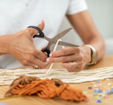  Una persona usa tijeras para cortar cordón de algodón para un proyecto de macramé