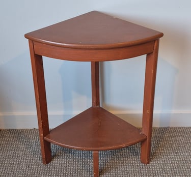 Vintage reddish-brown wooden corner side table with two tiers on a grey carpet.