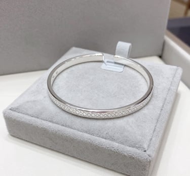 Minimalist semijoias in gold tones placed beside a small green plant for a fresh look.