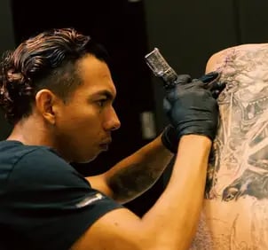Steven Aguirre, tatuador en Valencia, realizando un tatuaje profesional a un cliente en su estudio