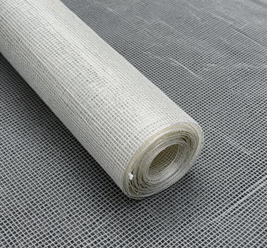 Close-up of sturdy fiberglass mesh being unrolled on a construction site under bright sunlight.