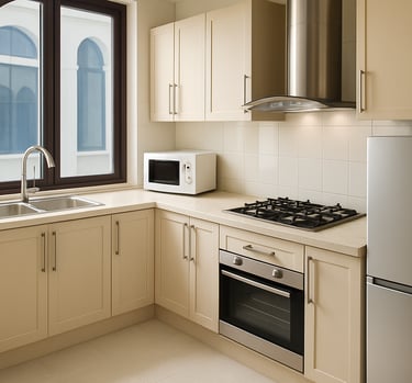 Modern cream kitchen cabinets with a stainless steel stove, oven, and refrigerator near a window.