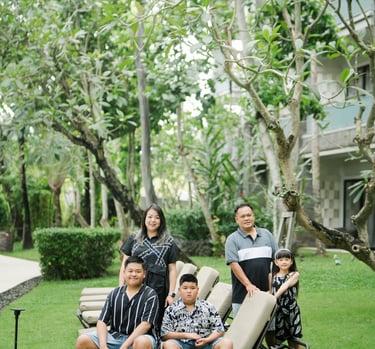family photography at Movenpick Jimbaran Bali with parents and children sitting together on a green garden lawn