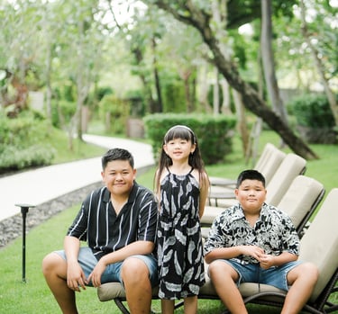 family sitting together on a garden lawn during a relaxed family photography session at Movenpick Jimbaran Bali