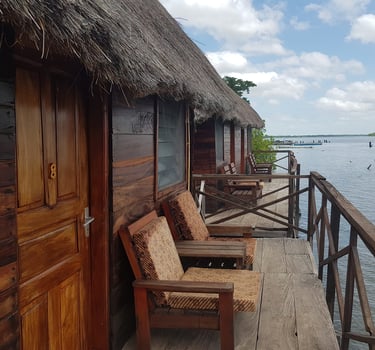 A picturesque view of Bintang Bolong Lodge, showcasing wooden stilt houses situated along the calm w