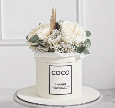a chanel perfume bottle with flowers in a white container