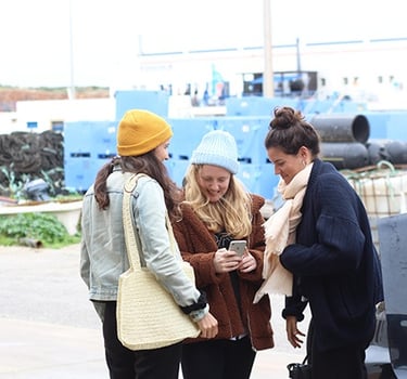 three women standing in front of a car