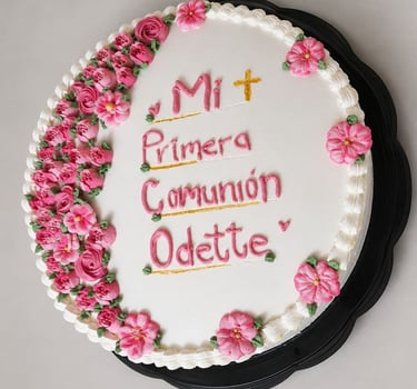 pastel con flores rosas y la leyenda "Mi primera comunión"
