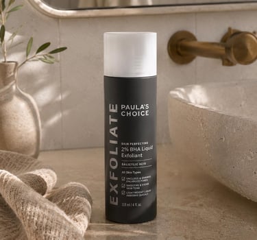 Paula’s Choice 2% BHA Exfoliant on a bathroom countertop beside a stone sink