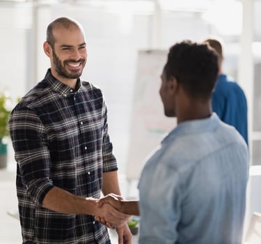 A smiling businessman shaking hands with a colleague in a bright office setting.