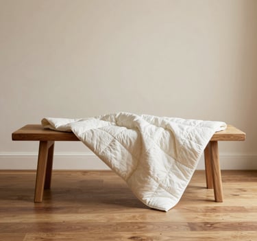 Lifestyle shot of the Horizon Quilt draped over a minimalist wooden bench. The setting is a bright, airy studio with warm cream walls and polished wood floors. The mood is tranquil and sophisticated.