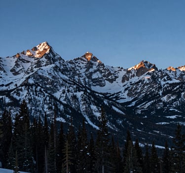 A breathtaking wide-angle landscape photograph of the Rocky Mountains in North America during the blue hour. The image shows incredible detail in the snow-capped peaks and evergreen trees, demonstrating high dynamic range.