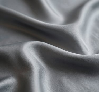 An abstract, artistic macro shot of silk fabric and light reflections, creating a sense of luxury and texture, using the brand's matte color palette.
