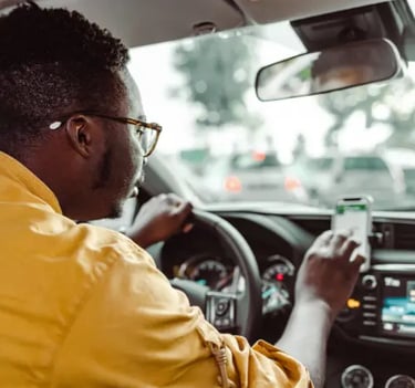 A rideshare driver using a smartphone GPS navigation app while driving a car in city traffic.