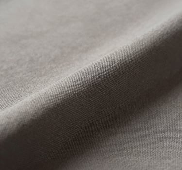 Close-up artistic photograph of textured fabric in shades of #6B625E and #AEAEA7. The lighting is soft and cinematic, highlighting the intricate weave. Minimalist composition with a dark #26211F shadow in the corner. Sophisticated and professional style.