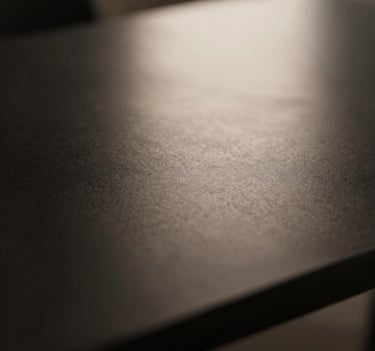 A sophisticated, minimalist close-up of light reflecting off a dark, polished surface, featuring deep blacks and soft beige highlights, artistic and refined composition.