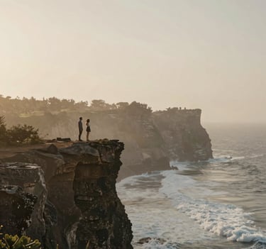 Wide shot of a couple standing on a rugged Uluwatu cliff edge, the Indian ocean crashing below, soft misty sunrise light, earthy #7B6654 tones, serene and elegant composition reflecting minimalist beauty.