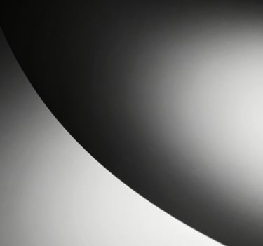 Abstract black and white macro photography of light hitting a curved surface, creating a smooth gradient from deep charcoal black to pure white, high-craft feel.
