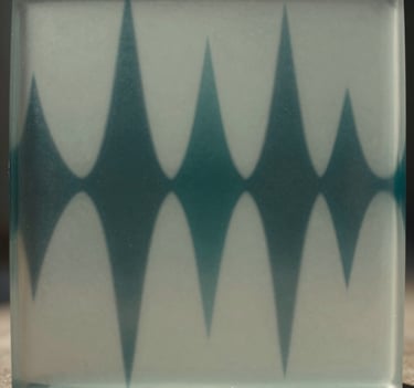 Abstract cinematic photography of light refracting through a heavy block of milky glass. The light creates distorted prisms in muted sage grey and deep teal, mimicking the visual representation of invisible frequency waves.