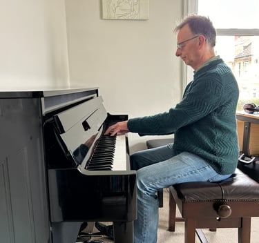 Photo of Steven playing an upright piano