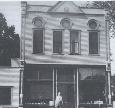 a two story white building with a man standing in front of it