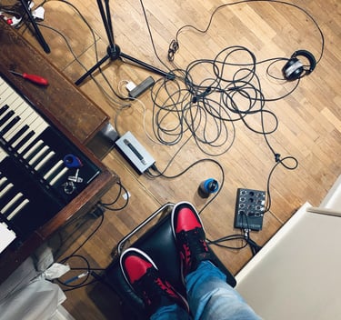 Studio floor with cables, Hammond keys and red sneakers visible