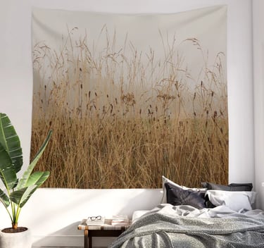 Wall tapestry hanging on a bedroom wall with bed underneath it and bedding on bed
