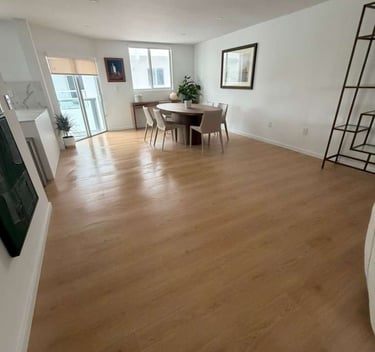 Modern open concept living area featuring light oak hardwood flooring and a minimalist dining set.