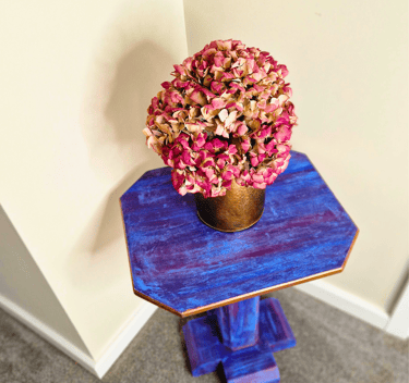 A bright plant or lamp stand painted in a boho style with gold edging