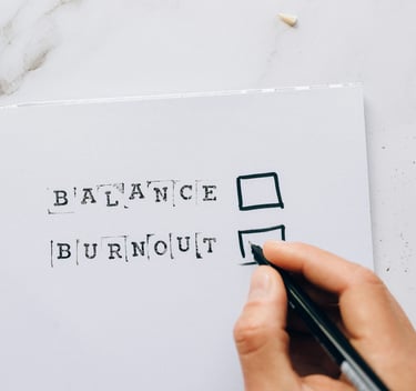a person holding a pen ticking the box for balance versus burnout