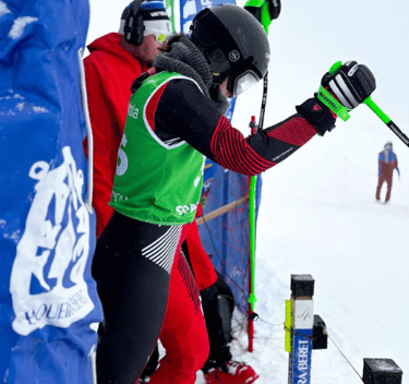 a person in a green and red outfit is holding skis