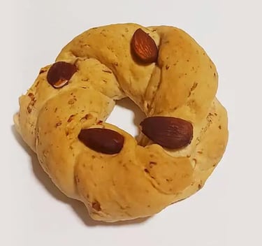 Golden brown Italian taralli pastry with whole almonds on a white background.