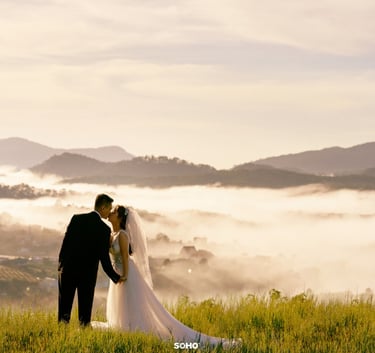 a bride and groom standing on a hill overlooking a valley