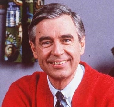 Mr. Rogers smiling in a red sweater and tie