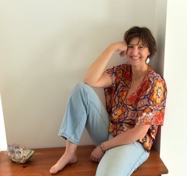 julie mansencaut sitting on a wooden bench with a bookcase