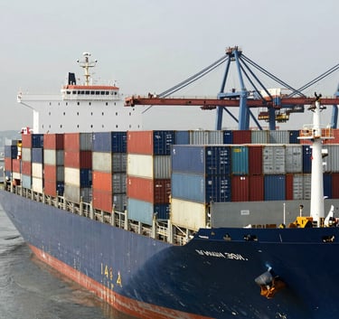A wide-angle landscape shot of a massive cargo ship loaded with metal shipping containers at a busy commercial port, Global / Industrial B2B, daylight, reflecting the scale of international metal trade.